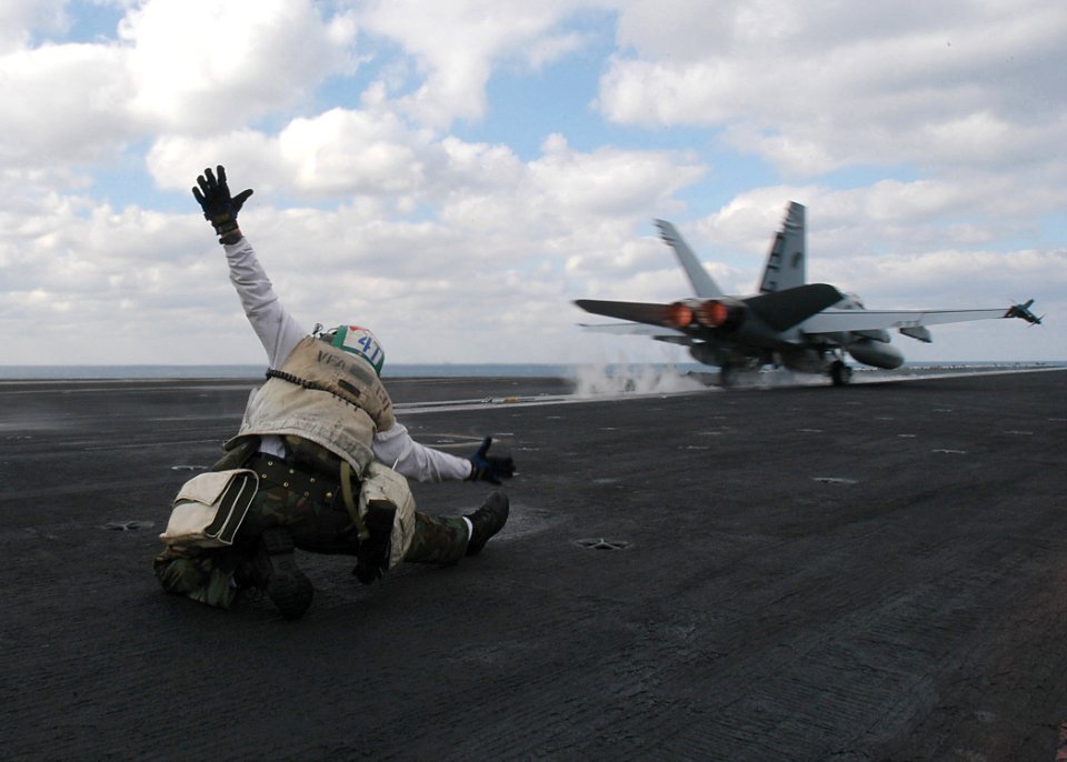 US Navy 031207-N-3986D-001 A troubleshooter from the Wildcats of Strike Fighter Squadron One Three One (VFA 131) signals a go launch for a F-A-18 Hornet