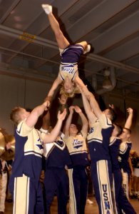 US Navy 031229-N-9693M-004 U.S. Naval Academy (U.S.N.A.) Cheerleader Midshipmen 4th Class Jaime Bradley, from The Woodlands, Texas, is flipped upside down during the EV1.Net Rodeo Pep Rally in Reliant Arena