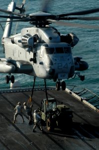 US Navy 031209-N-6895M-003 Combat Cargo crewmembers secure a forklift to a U.S. Marine Corps CH-53 Sea Stallion helicopter to transport from the flight deck aboard USS Peleliu (LHA-5)