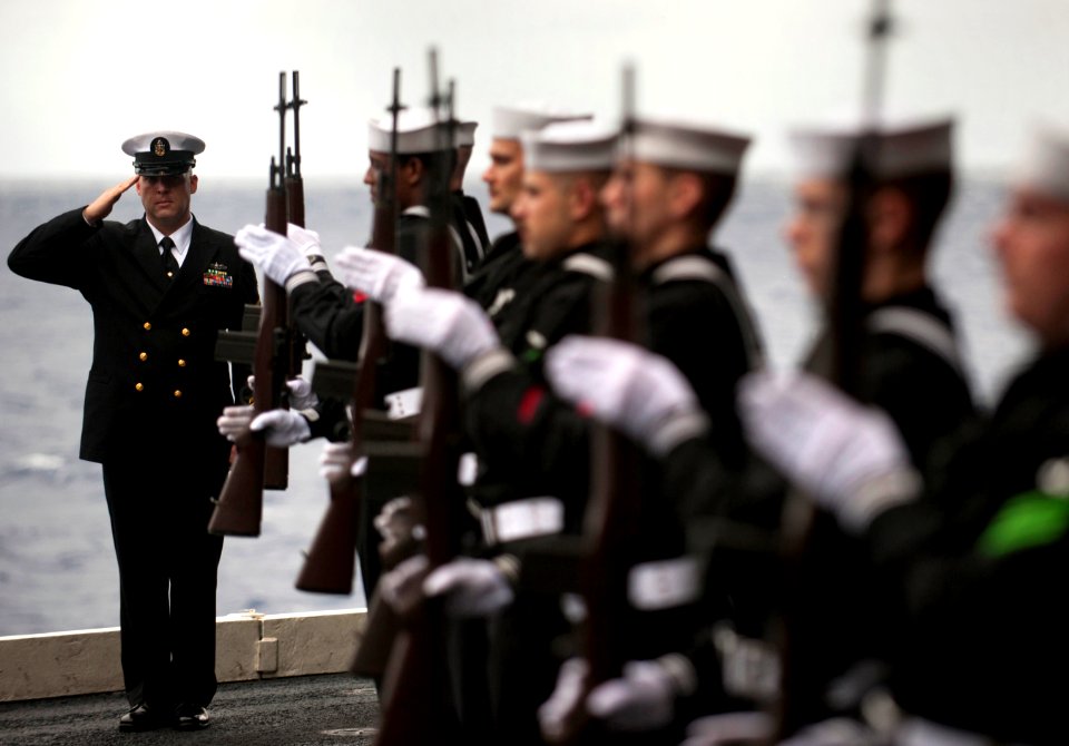 US Navy 101227-N-7981E-260 enior Chief Gunner's Mate Zachary Eubank salutes during a burial at sea aboard USS Carl Vinson (CVN 70)