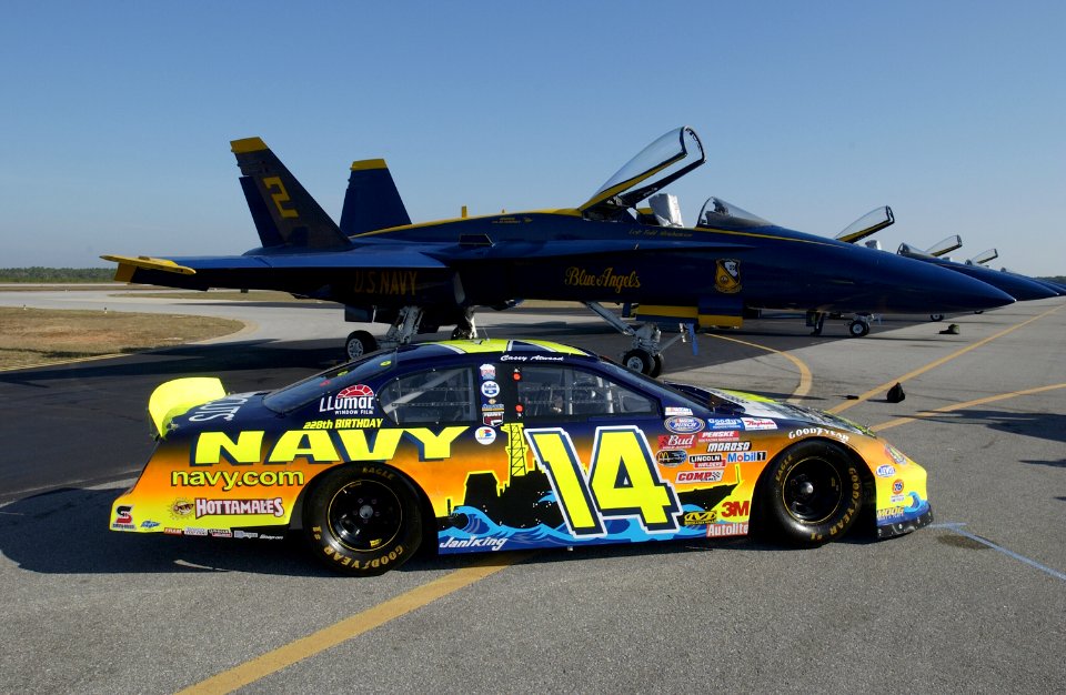 US Navy 031108-N-5862D-008 The Navy sponsored Chevrolet Monte Carlo Busch Series race, show car is parked on the tarmac near F-A-18 Hornets assigned to the Navy's flight demonstration team, the Blue Angels, at Sherman Field