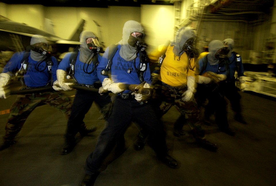 US Navy 040129-N-5319A-002 Members of the ship's hangar bay firefighting and damage control team advance on a simulated aircraft fire in hanger bay 2 aboard USS George Washington (CVN 73)