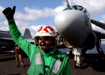 US Navy 040224-N-4374S-001 A flight deck chief assigned to the Scorpions of Electronic Attack Squadron One Three Two (VAQ-132) signals flight deck directors that his aircraft is ready for flight quarters photo