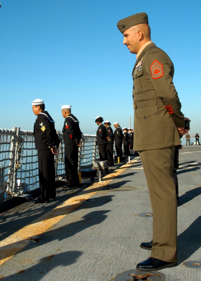 US Navy 032807-N-7029R-024 Gunnery Sgt. Octavio Gonzalez looks on as Sailors man the rails on board USS Pearl Harbor (LSD 52) during the departure ceremony