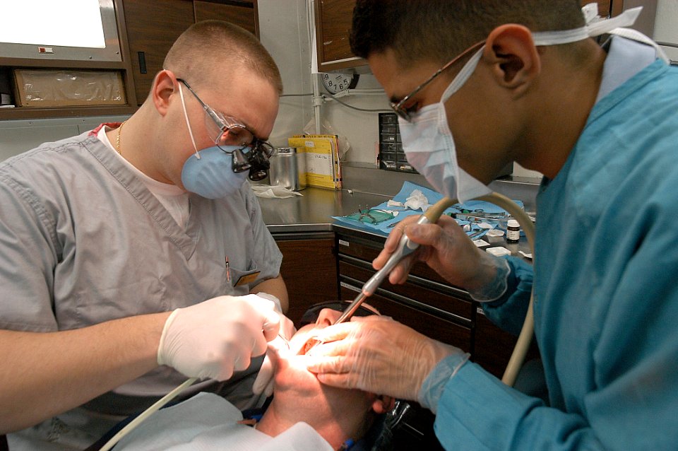 US Navy 040126-N-3986D-001 Lt. Joe Wigfield, from Magnolia, Ohio, and Dental Technician Miguel Hernandez from Puerto Rico, apply a tooth filling to a crew member aboard USS George Washington (CVN 73)