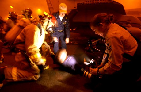 US Navy 040309-N-5319A-004 Photographer's Mate 2nd Class Summer Anderson videotapes a fire fighting team helping mock causalities during an Improvised Explosive Device (IED) and Mass Causality exercise in the hangar bay