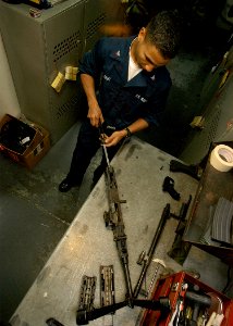 US Navy 040214-N-3986D-001 Aviation Boatswain's Mate Handler 3rd Class Eddy Cruz, of Rochester, N.Y., disassembles a 7.62mm caliber M240B machine gun in the ship's armory aboard the nuclear powered aircraft carrier