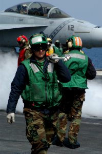 US Navy 040321-N-5821P-001 Aviation Boatswain's Mate Airman Billy Kennedy clears one of four catapults on the ship's flight deck of its holdback bar, as the flight deck makes its transition from launch mode to recovery