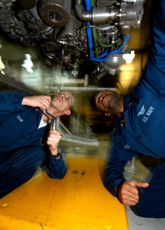 US Navy 040227-N-4190W-001 Aviation Machinist's Mates install a drain on an F-A-18C Hornet engine in the Jet Shop aboard USS John F. Kennedy (CV 67)