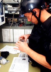 US Navy 040224-N-4374S-016 A member of the Vessel, Board, Search, and Seizure (VBSS) team assigned to the guided missile destroyer Roosevelt takes a photograph of documents while gathering intelligence