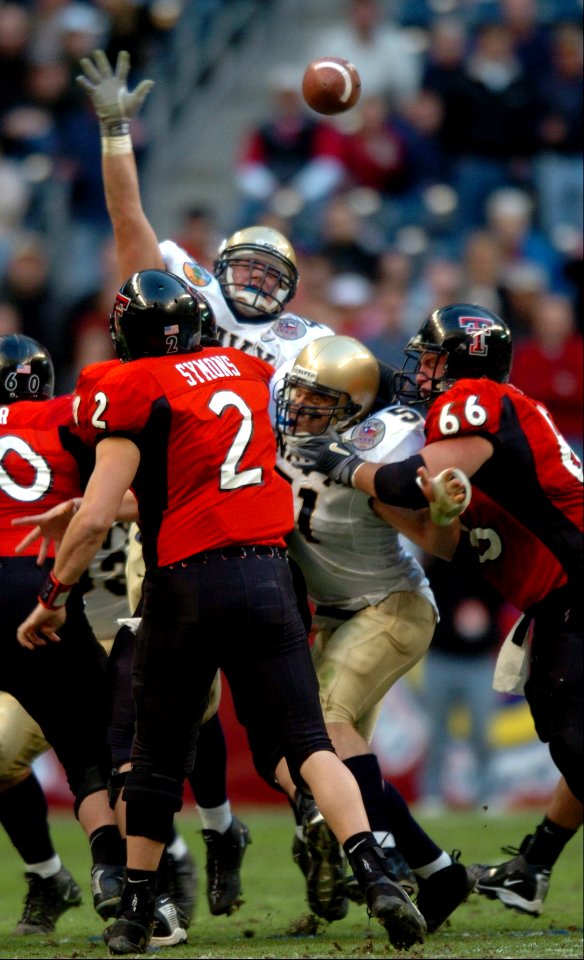 US Navy 031230-N-2653P-748 Texas Tech quarterback B.J. Symons passes the ball as Navy linebacker Bobby McClarin leaps into the air in an attempt to block during the Naval Academy's game with Texas Tech in the EV1.Net Houston Bowl