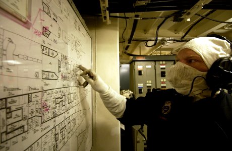 US Navy 040214-N-5319A-004 A crewmember aboard the Canadian Navy Halifax-class patrol frigate HMCS Toronto (FFH 333), examines a damage control status board during one of many firefighting drills conducted while underway photo
