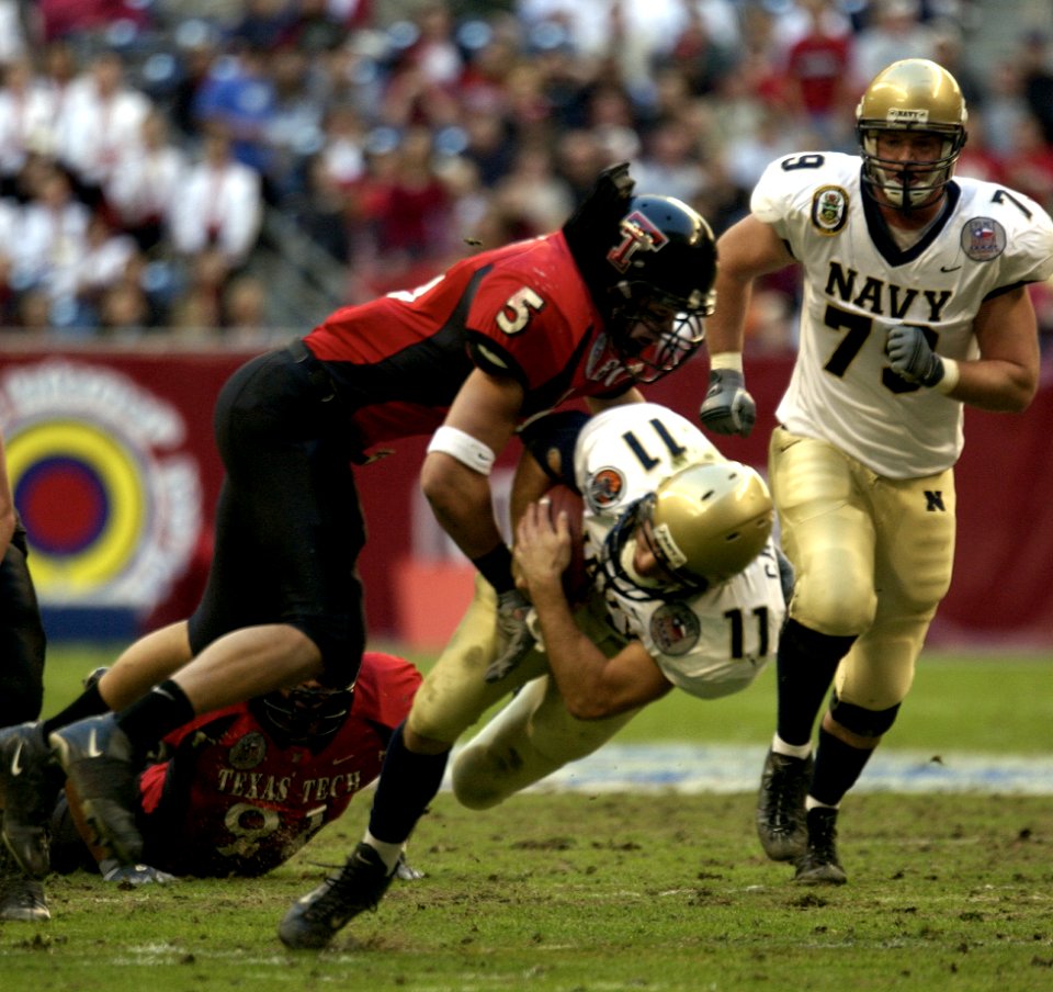 US Navy 031230-N-9693M-006 Navy quarterback Craig Candeto is tackled by Texas Tech linebacker John Saldi on a rushing attempt during the EV1.Net Houston Bowl at Reliant Stadium in Houston, Texas