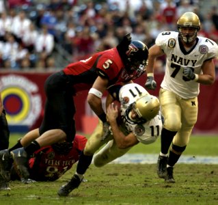 US Navy 031230-N-9693M-006 Navy quarterback Craig Candeto is tackled by Texas Tech linebacker John Saldi on a rushing attempt during the EV1.Net Houston Bowl at Reliant Stadium in Houston, Texas