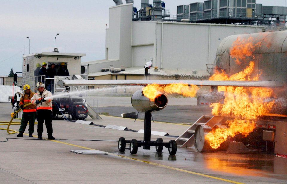 US Navy 040303-N-5821W-002 Aviation Boatswain's Mate 1st Class Stephen Mark, NAS Sigonella Fire Department assistant training officer, and Ron Hall, NAS Sigonella Fire Department battalion chief, battle a fire while training wi