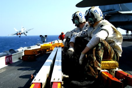 US Navy 040228-N-5821P-009 Aviation Machinist's Mate 3rd Class Ryan Nunez, of Los Angeles, CA, and Aviation Electronics Technician 3rd Class Ricky Steele, of Antlers, OK, take a break on the flight deck as an F-A-18C Hornet launches