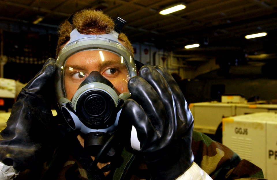 US Navy 040413-N-5821P-002 Hull Maintenance Technician Fireman Earl Perkins, of Huffman, Texas, relaxes his gas mask during a chemical, biological, radiation (CBR) general quarters (GQ) drill