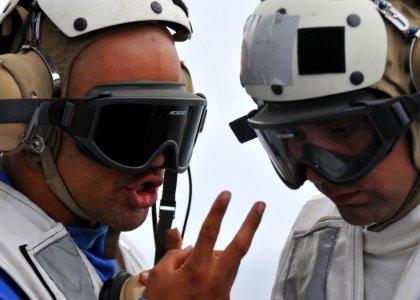US Navy 110625-N-PB383-500 Operations Specialist 3rd Class Brandon Lamm relays information to Boatswain's Mate 2nd Class Mark Fears during deck lan