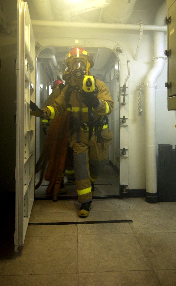 US Navy 040309-N-5319A-006 A fire fighting hose team investigates smoke on the forward mess decks during an Improvised Explosive Device (IED) and Mass Causality drill aboard USS George Washington (CVN 73)