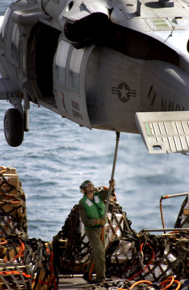 US Navy 040408-N-5319A-002 A sailor assigned to the Military Sealift Command (MSC) combat support ship USNS Supply (T-AOE 6), attaches a load of cargo to an MH-60S Knighthawk