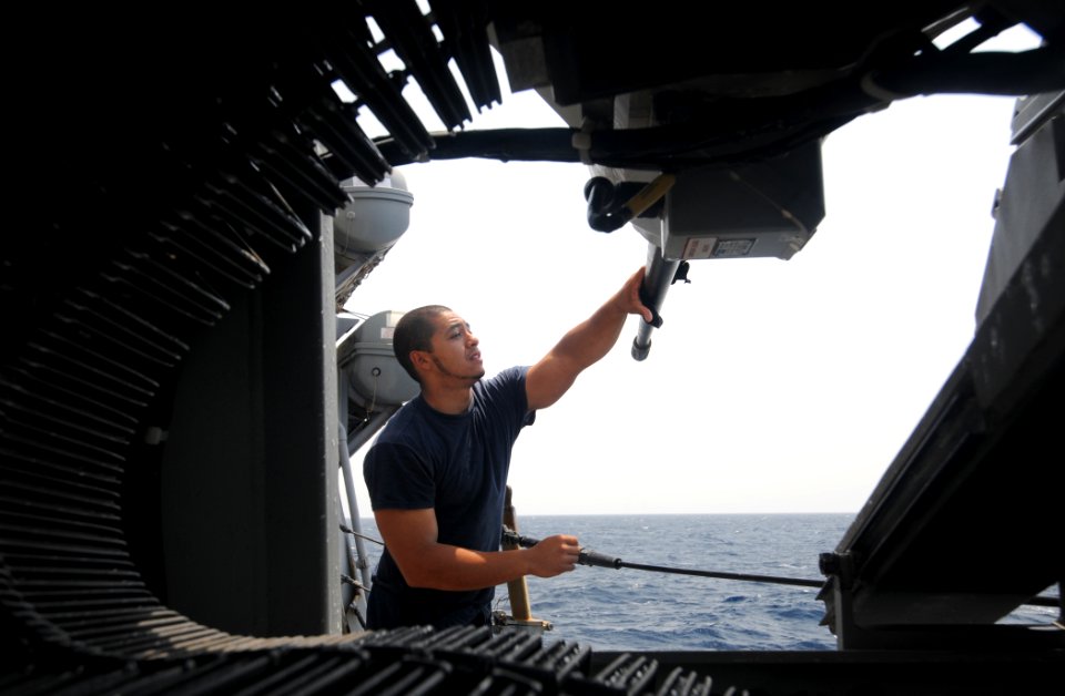 US Navy 110730-N-XQ375-119 Gunner's Mate 3rd Class Augustin Villatoro cleans an MK 38 25 mm machine gun aboard USS Mitscher (DDG 57)