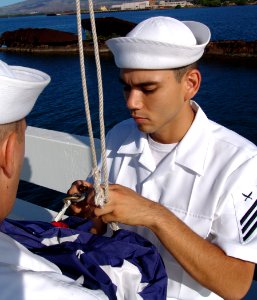 US Navy 040531-N-9643K-009 Yeoman Seaman Gabriel Gonzales assigned to the Los Angeles-class submarines USS Greeneville (SSN 772) prepare to bring the flag to half-mast