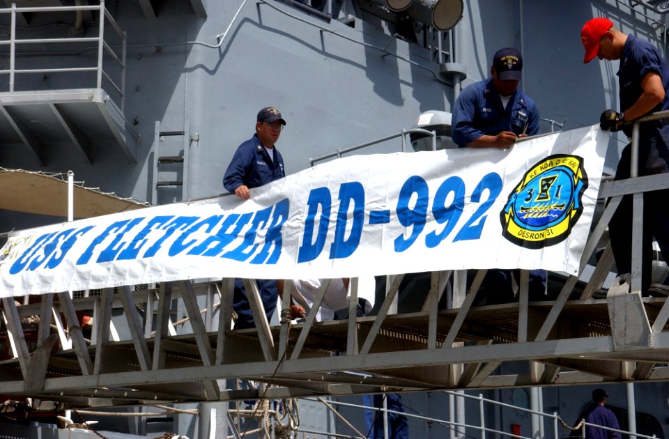 US Navy 040525-N-3019M-003 Sailors assigned to the Spruance Class destroyer USS Fletcher (DD 992) attach the ship's banner to the brow after returning to Pearl Harbor for a two-day port visit