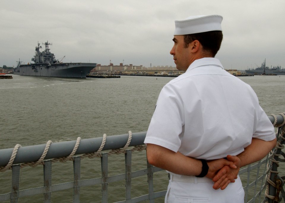 US Navy 040607-N-4374S-004 A Sailor assigned to the fast combat support ship USS Seattle (AOE 3) mans the rails as the ship gets underway for a regularly scheduled deployment as part of the USS John F. Kennedy Strike Group