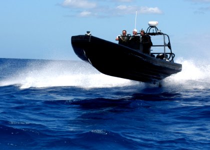US Navy 040528-N-3019M-006 Quartermaster 1st Class Tony Sasser, assigned to Afloat Training Group, Middle Pacific (ATGMIDPAC), simulates a nine-meter Rigid Hull Inflatable Boat (RHIB) terrorist attack during an anti-terrorism e photo