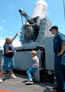 US Navy 040405-N-3019M-004 Tom Hayden, whose son is stationed aboard the guided missile frigate USS Crommelin (FFG 37) explains to his grandson and Fire Controlman 2nd Class Charlie Romero how guns have changed since he served
