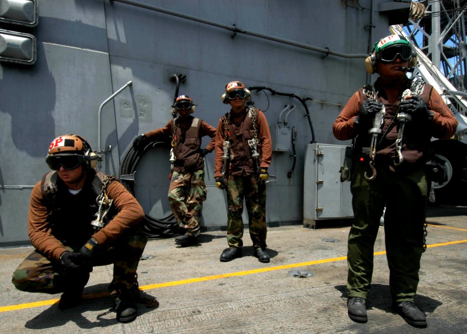 US Navy 040610-N-4190W-002 Four Plane Captains aboard USS John F. Kennedy (CV 67) take a short break in their daily routine, as they prepare to secure aircraft to the flight deck with aircraft tie-down chains