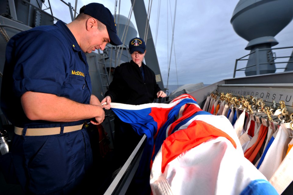 US Navy 111204-N-YZ751-060 Ensign Michael C. McDonald and Ensign Elyse Yarbrough prepare flags during a flag hoist training exercise aboard guided