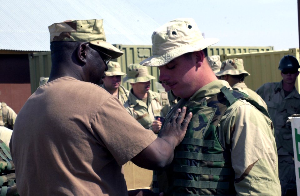 US Navy 040307-N-0683T-016 Chief Storekeeper Troy McClanahan, assigned to Naval Mobile Construction Battalion Seven Four (NMCB-74), helps Construction Electrician Constructionman Brandon Belew get properly fit in his body armor