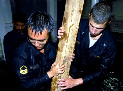 US Navy 040603-N-4104L-005 Lt. j.g. Chris Cortez, Repair Division Officer assigned to the guided missile destroyer USS Russell (DDG 59), and a Republic of Singapore Navy (RSN) Sailor use shoring material to repair damage during