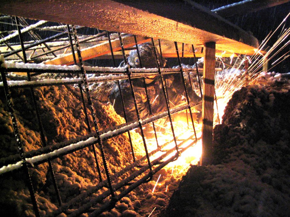 US Navy 040323-N-0000X-001 Steelworker 2nd Class Brian King cuts reinforcing steel rebar during a snowstorm the night prior to a scheduled concrete pouring operation