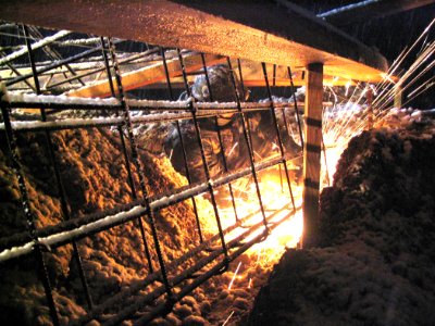 US Navy 040323-N-0000X-001 Steelworker 2nd Class Brian King cuts reinforcing steel rebar during a snowstorm the night prior to a scheduled concrete pouring operation