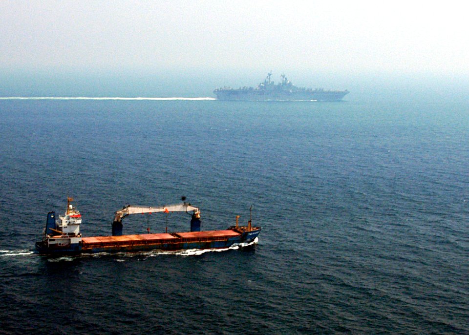 US Navy 040705-N-2972R-040 A merchant ship sails off the starboard side of the amphibious assault ship USS Kearsarge (LHD 3) while transiting the Straits of Hormuz