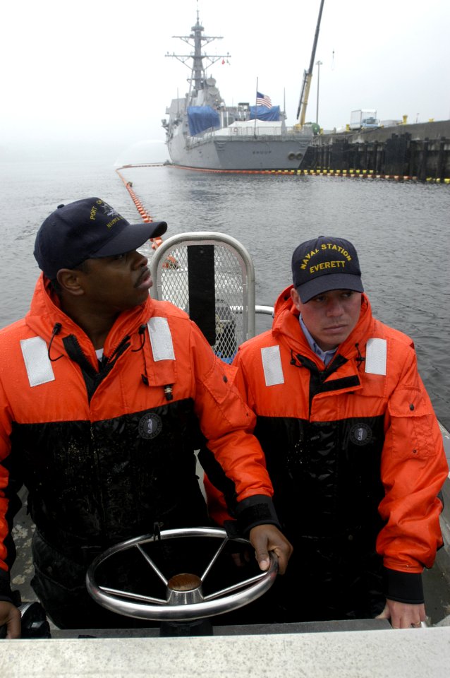 US Navy 040610-N-6477M-055 Boatswain's Mates 2nd Class Sorrells Claiborne and Matthew C. Turner assigned to Port Operations at Naval Station Everett, position Oil Containment Booms around the ships