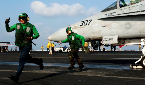 US Navy 120115-N-OY799-181 Sailors clear the launching area as an F-A-18C Hornet prepares to launch