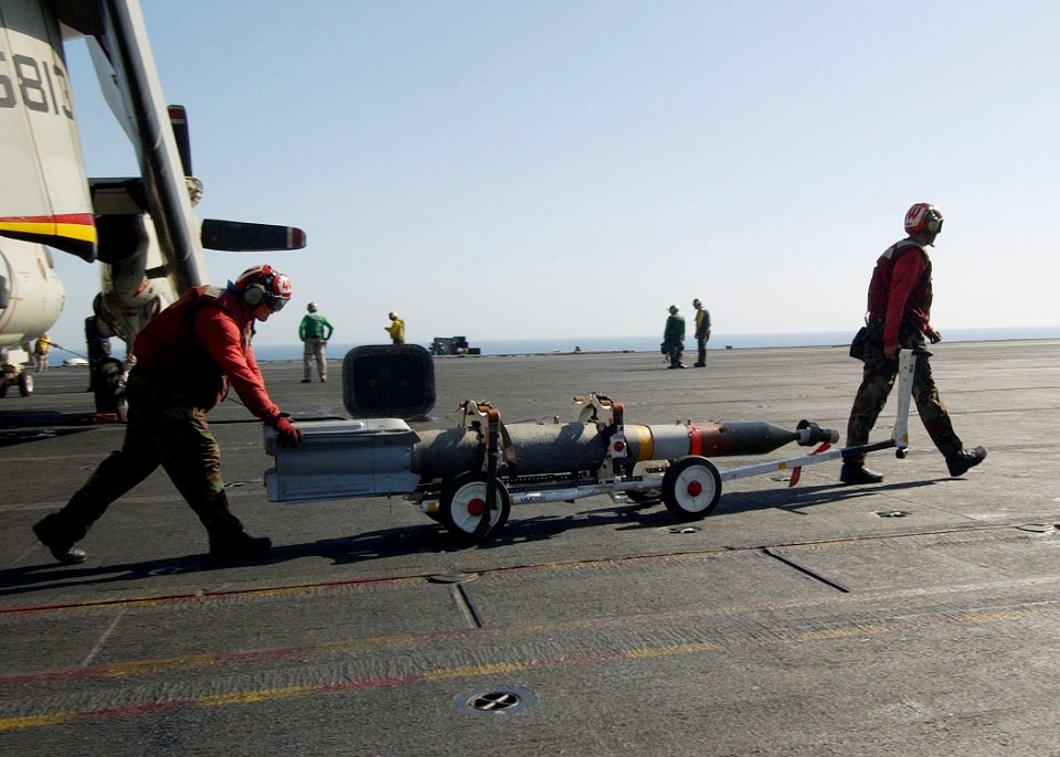 US Navy 040714-N-4374S-001 Aviation Ordnancemen transfer Guided Bomb Unit Twelve (GBU-12) bombs to an F-A-18 Hornet for ordnance on-load aboard the aircraft carrier USS John F. Kennedy (CV 67)