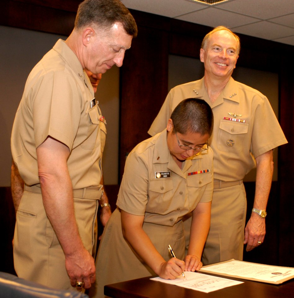 US Navy 040722-N-9693M-005 Chief of Navy Chaplains, Rear Adm. Louis V. Iasiello, left, watches with Commander, Naval Reserve Force, Vice Adm. John Cotton as newly commissioned Ensign Jeanette Gracie Shin signs her Oath of Offic