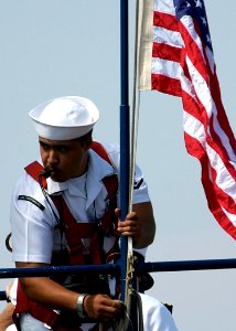 US Navy 040812-N-6811L-124 Machinist's Mate 3rd Class Adan Rodriguez raises the National Ensign as the Los Angeles class fast attack submarine USS Portsmouth (SSN 707) prepares to get underway photo