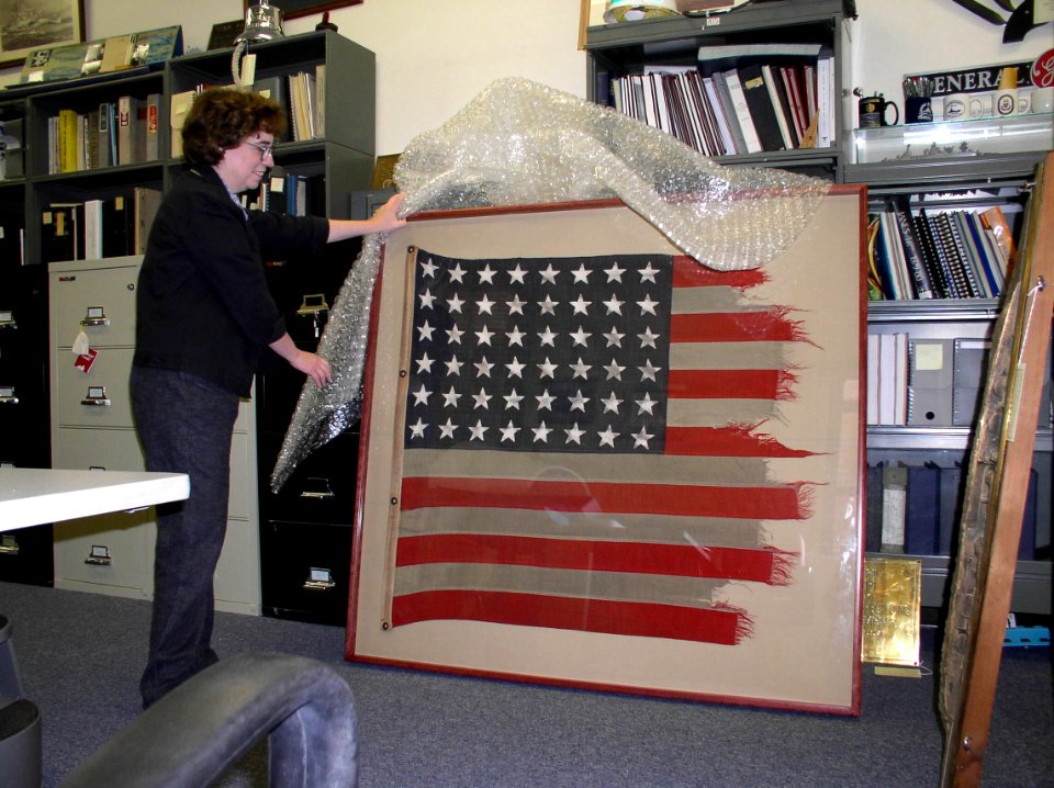 US Navy 040615-N-6236G-004 Karen France, Curator with the Naval Historical Center (NHC), examines the World War II battle flag of the destroyer USS Zellars (DD 777) after its recent conservation