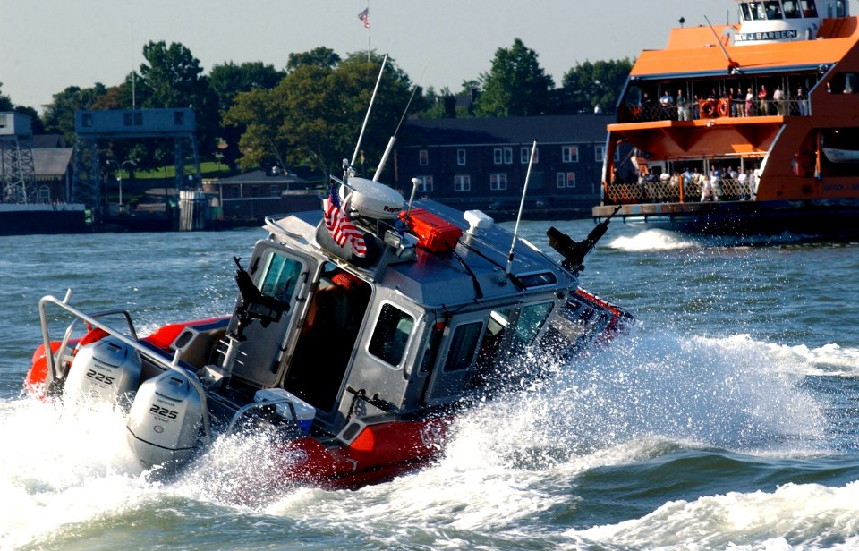 US Navy 040901-C-4938N-085 A 25-foot Defender Class security boat attached to the Coast Guard Maritime Safety and Security Team 91106 sweeps the East River around Whitehall Terminal as the Staten Island Ferry arrives to Manhatt