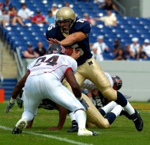 US Navy 040911-N-9693M-015 U.S. Naval Academy Midshipman 1st Class Frank Divis gains yardage against the Northeastern Huskies' EJ Jackson