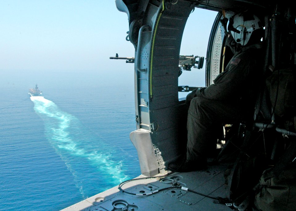 US Navy 040705-N-2972R-011 Aviation Electronics Technician 3rd Class James Woodward, seated in an MH-60S Knighthawk helicopter keeps watch on the waters around the amphibious assault ship USS Kearsarge (LHD 3) transits the Stra