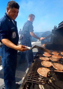US Navy 040920-N-3019M-006 Boatswain's Mate 1st Class Jesse Rodriguez cooks hamburgers, hot dogs and chicken for family members
