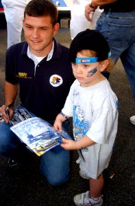 US Navy 040925-N-4729H-518 NASCAR driver Casey Atwood signs a picture for a young race fan at the Dover International Speedway in Delaware