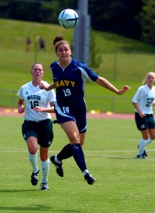 US Navy 040829-N-9694M-004 U.S. Naval Academy Midshipman Nicole Waggoner, foreground, heads the ball away from George Mason University's Allison Cowan during a regular season soccer match