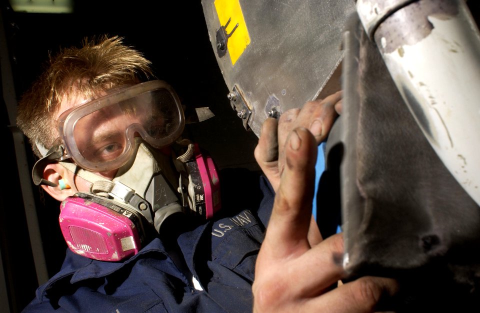 US Navy 040801-N-1485H-017 Aviation Support Equipment Technician 3rd Class Robert Herstien of Ft. Worth, Texas, sands paint off of a cart in the equipment service shop aboard USS Kitty Hawk (CV 63)